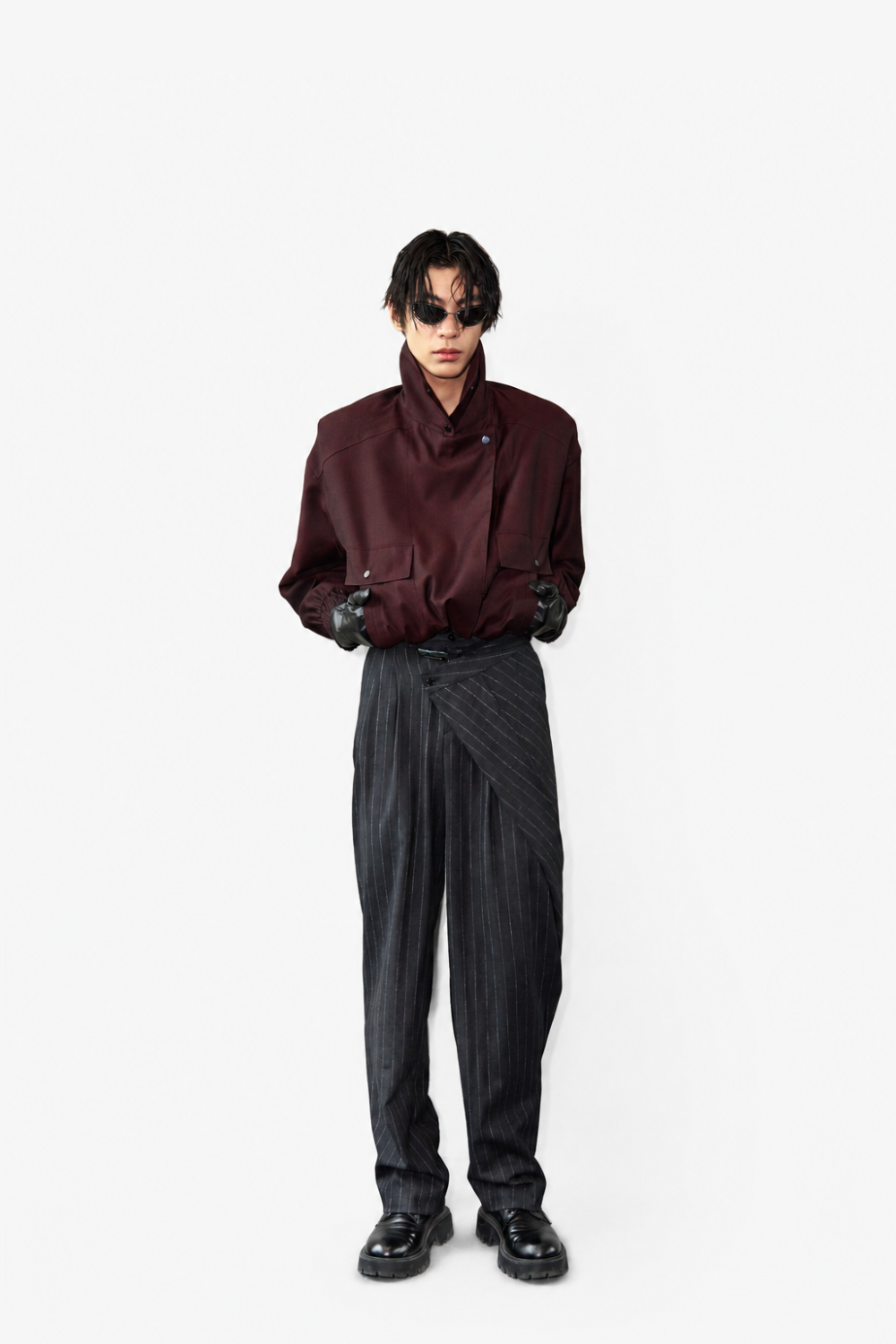 Model wearing Tailored Wool Balloon Bomber Jacket - Burgundy with a high structured collar and voluminous sleeves, paired with asymmetrical pinstriped trousers and black leather gloves, showcasing SHAO New York bespoke tailoring and a modern sculptural silhouette.