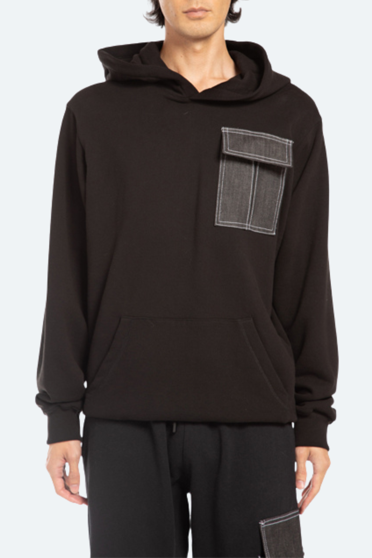 Front view of black oversized hoodie with cargo chest pocket and relaxed architectural fit
