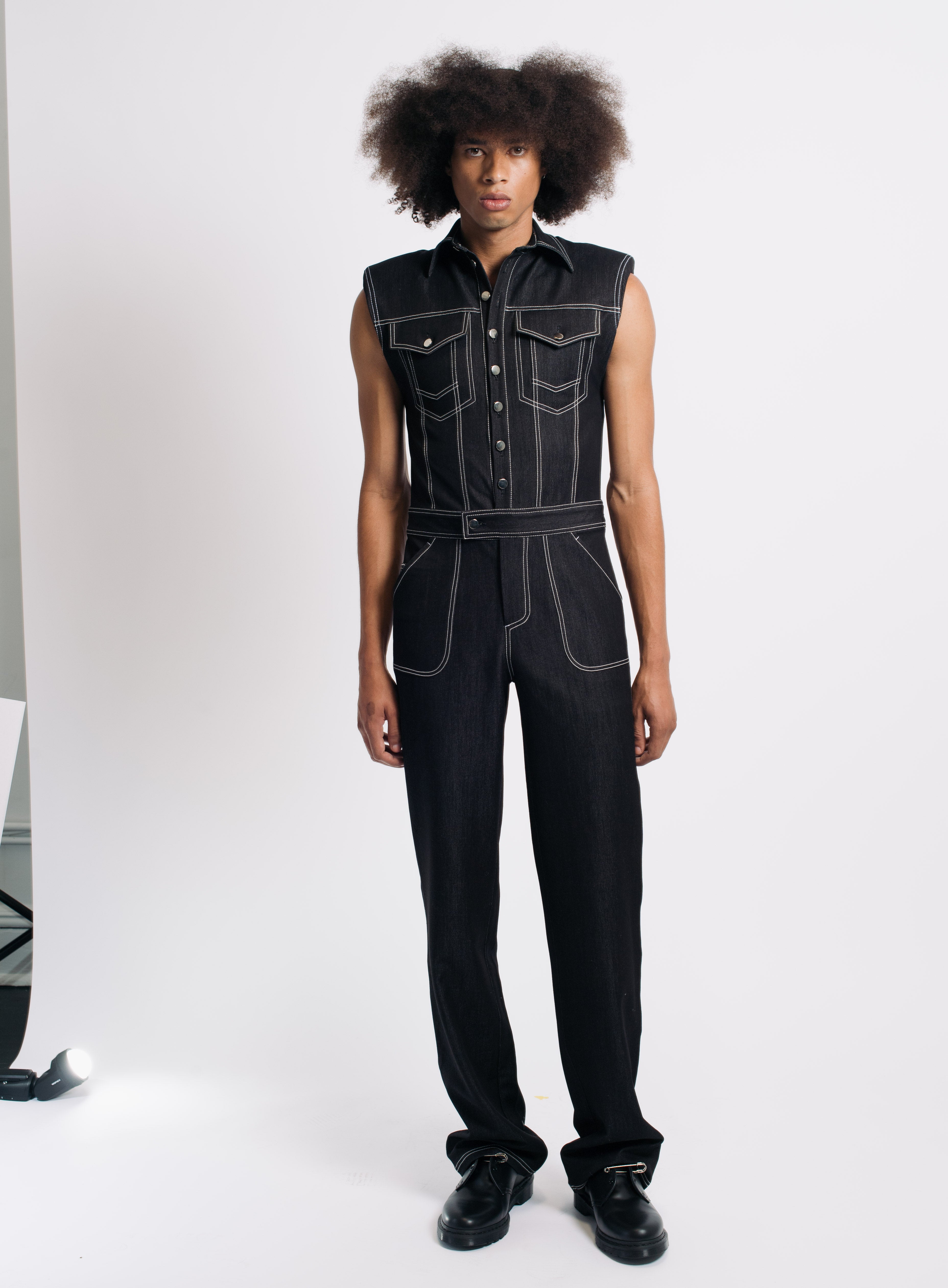 Black Contrast-Stitch Utility Denim Jumpsuit with sleeveless design, prominent front buttons, flap chest pockets, and defined white contrast stitching, showcasing SHAO New York bespoke tailoring.