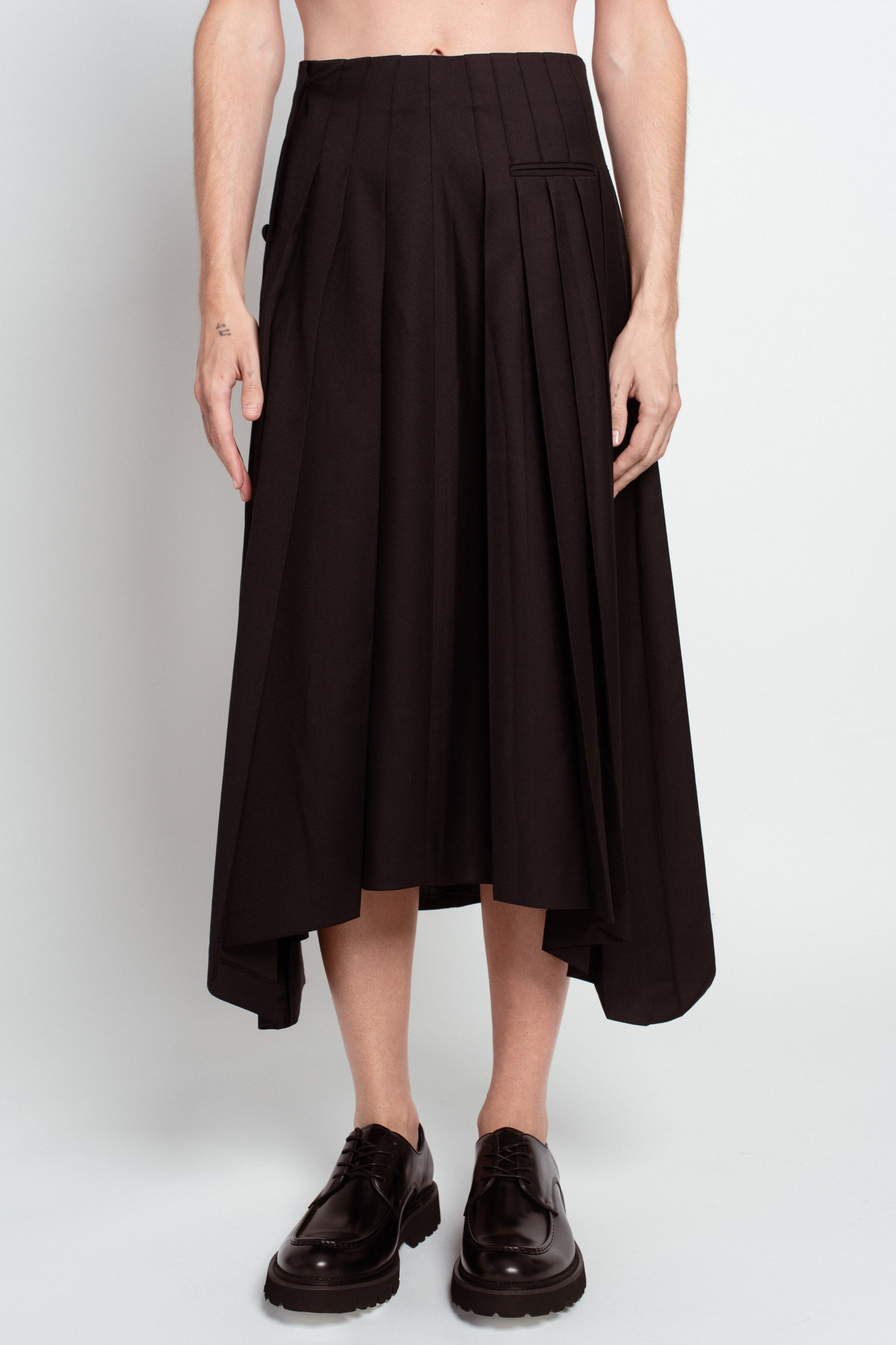 Front view of Jet Black Wool Wrap Skirt – Pleated Long Silhouette showcasing an asymmetric hem and refined pleating, embodying bespoke New York tailoring and luxury designer fashion.