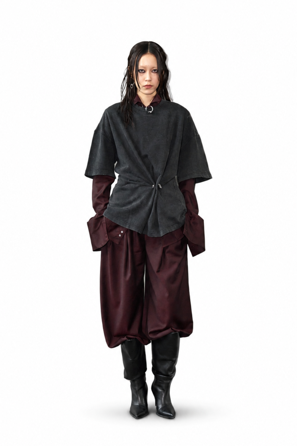 Model styled in Wool Barrel Pleated Trousers - Burgundy paired with layered dark tops and black pointed boots, showcasing a relaxed yet sculptural silhouette with luxury designer fashion influences.