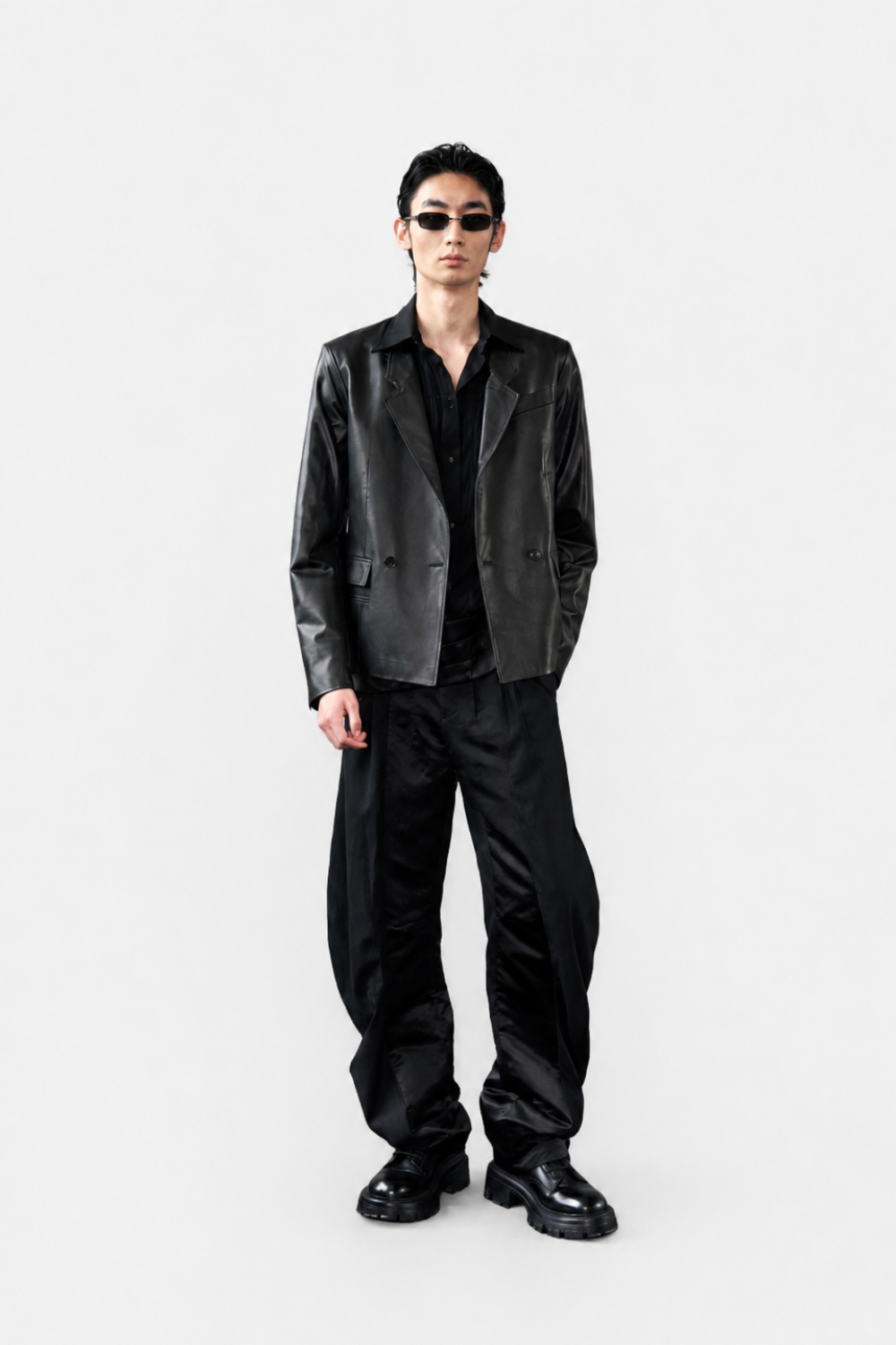 Model wearing Black Tailored Tuxedo Shirt styled under a sleek black leather jacket paired with wide-leg satin trousers and chunky black shoes, embodying SHAO New York’s luxury bespoke tailoring and modern sculptural silhouette.