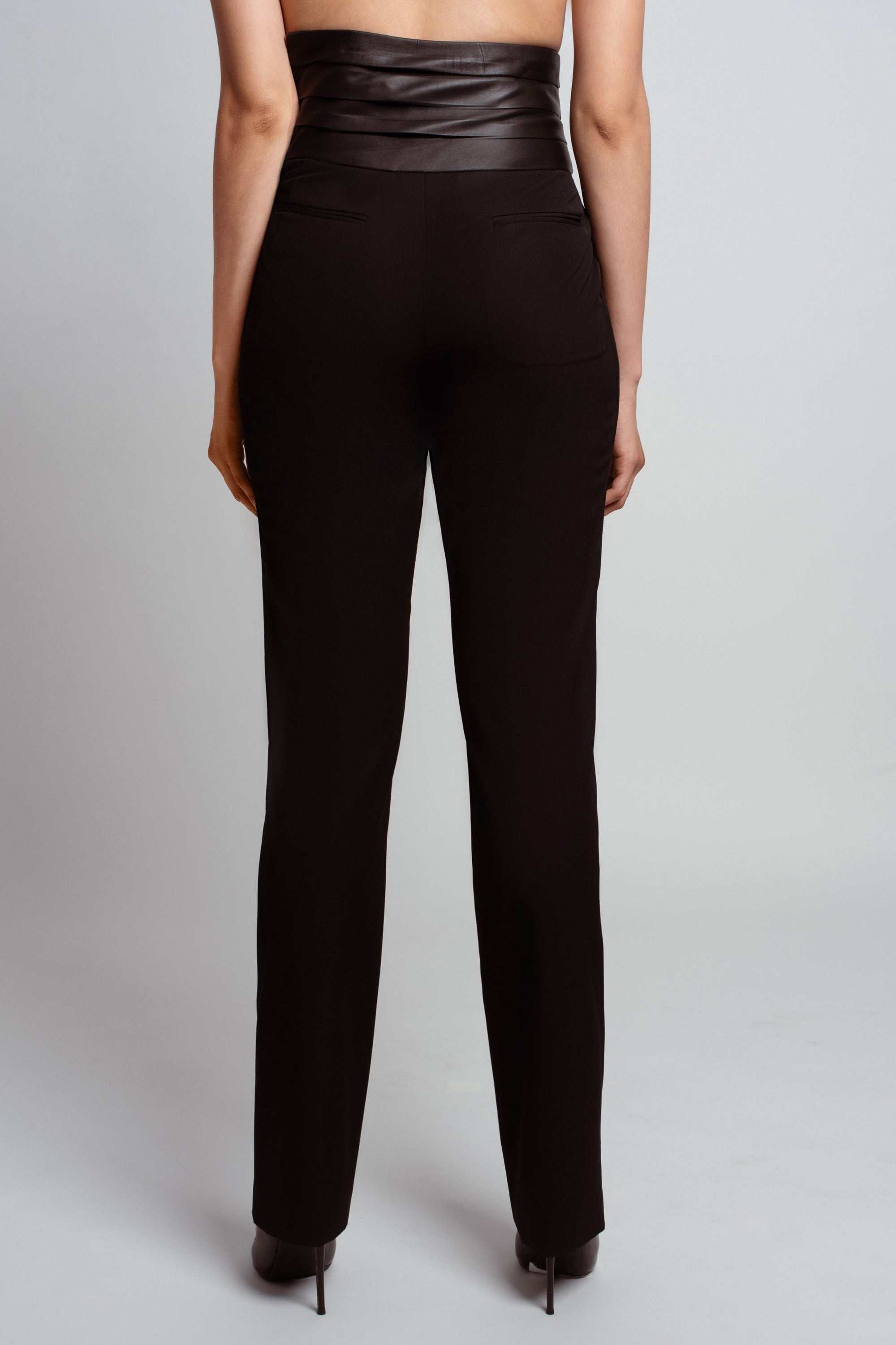 Rear view of Jet Black Tailored Trousers – Leather Cummerbund Detail showcasing a sleek high waist and streamlined silhouette in bespoke New York designer tailoring by SHAO New York.